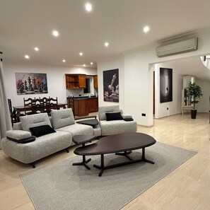A modern living room with a sectional sofa, a coffee table, and artwork on the walls.