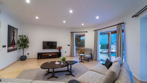 Un salon moderne avec un canapé, une table basse, un téléviseur et un balcon offrant une vue agréable.
