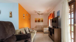 A living room with a sofa, a television, and artwork on the wall. - House With Barbecue Grill (Picarras)