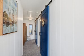 Un pasillo con una puerta azul, un espejo y un cuadro en la pared.