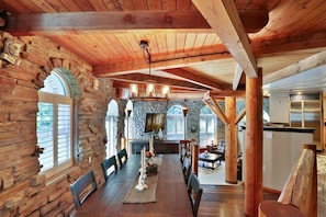 Un intérieur rustique avec une cheminée en pierre, des poutres en bois et un coin repas.