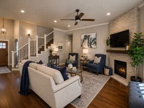 Una sala de estar con chimenea, televisor y escalera.