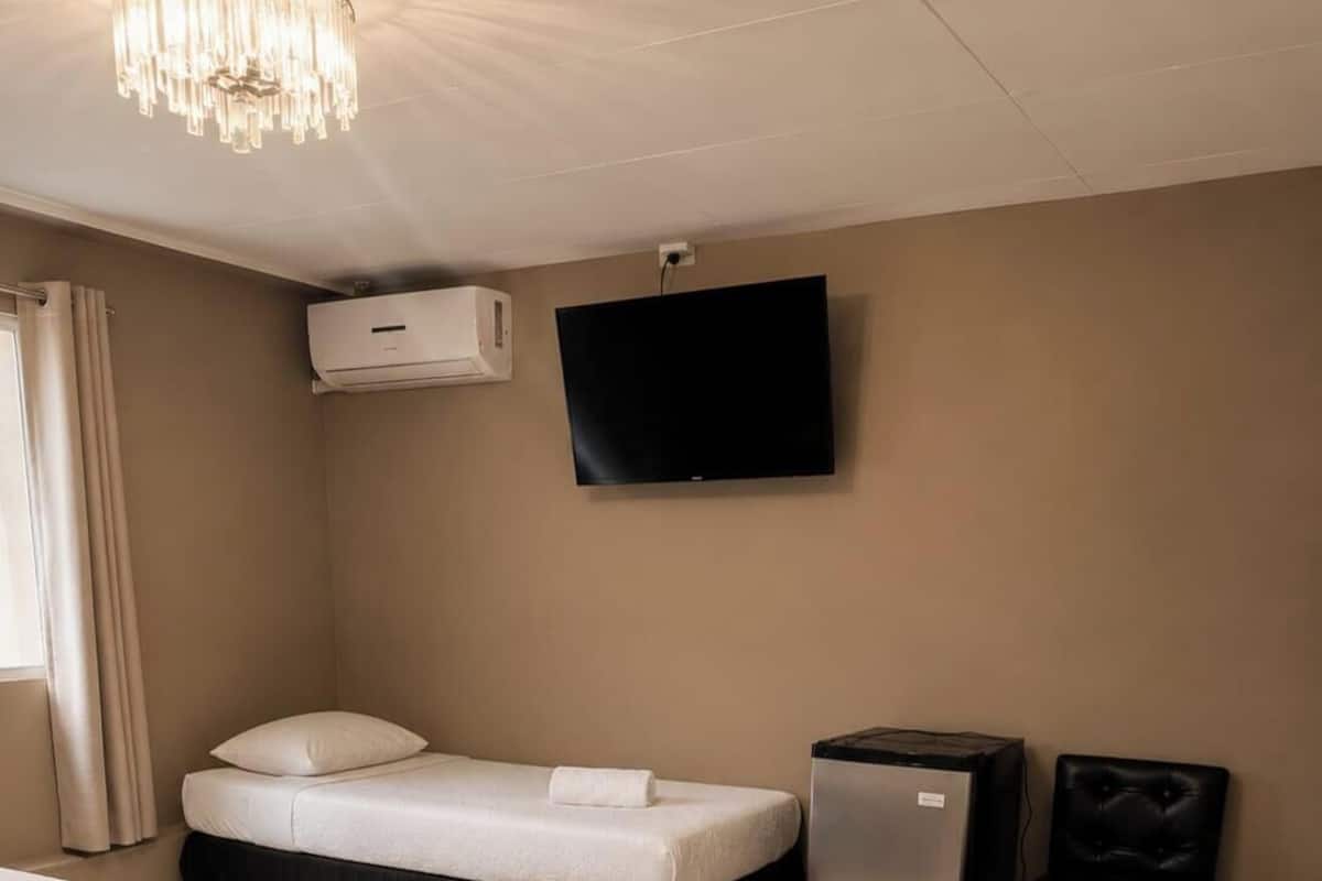 Hotellihuone, jossa on kaksi sänkyä, televisio, ilmastointilaite ja pieni pöytä.