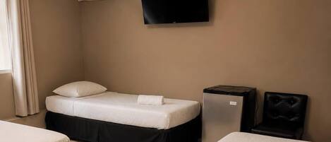 Une chambre d’hôtel avec deux lits, une télévision, un appareil de climatisation et une petite table.