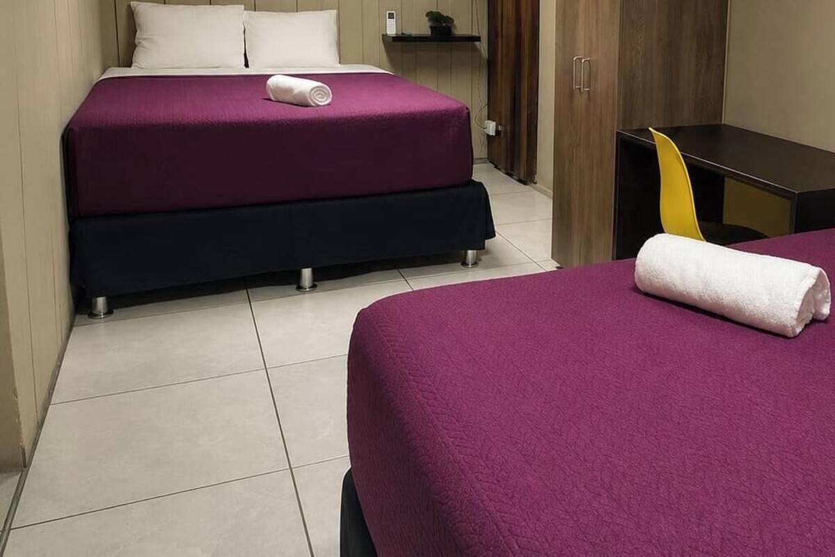 Hotellihuone, jossa on kaksi sänkyä, pieni pöytä, tuoli ja kaappi.