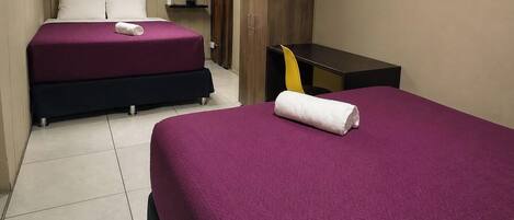 Una habitación de hotel con dos camas, una mesita, una silla y un armario.