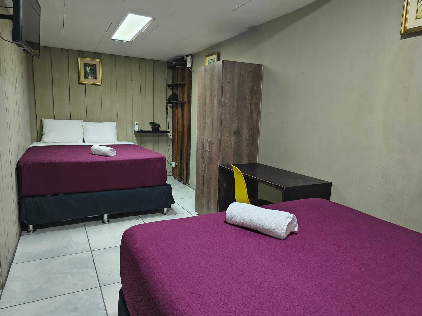 Ein Hotelzimmer mit zwei Betten, einem Holzschrank, einem Schreibtisch und einem Stuhl.