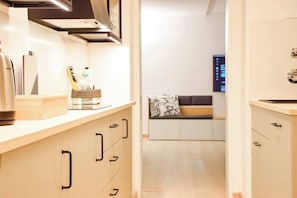 Une cuisine moderne avec des meubles en bois, une bouilloire en acier inoxydable et un plan de travail sur lequel se trouvent une bouteille d’eau et une boîte.