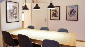 Kokoushuone, jossa on pitkä pöytä, neljä tuolia ja kolme riippuvalaisinta.