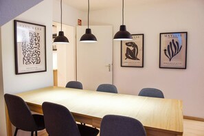 Une salle de conférence avec une longue table, quatre chaises et trois lampes suspendues.