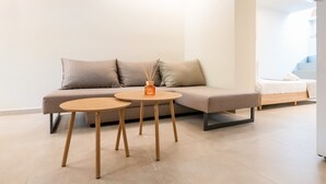 Ein modernes Wohnzimmer mit einer Couch, zwei kleinen runden Tischen und einem dekorativen Gegenstand auf der Couch.