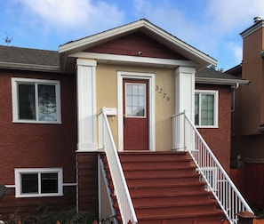 A two-story house with a red door, white railings, and a number '3279' on the wall.