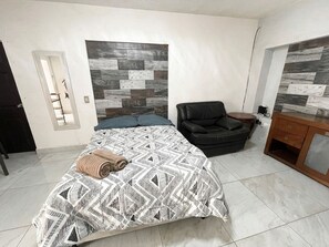 A bedroom with a bed, a chair, a dresser, and a wall with a geometric pattern. - Depto. Puente Internacional 
Alojamiento entero vivienda rentada en Reynosa Méx, (Reynosa)
