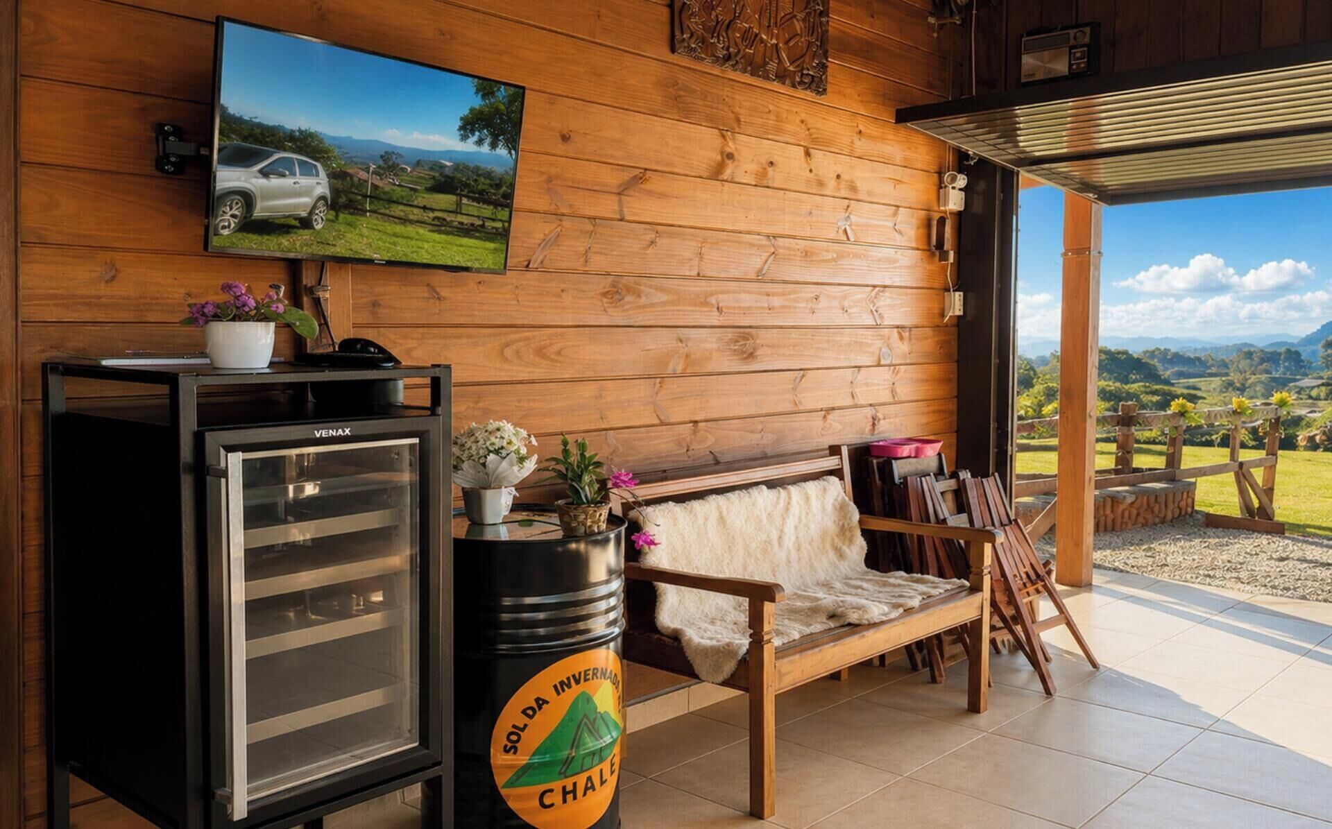 Ein Holzinnenraum mit Fernseher, Kühlschrank, Sitzbank und Blick ins Freie.