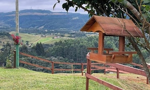 Un observatori de fusta amb una banca, envoltat per una tanca, amb vista a un paisatge amb ondulacions i una petita localitat a la distància.