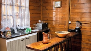 Una cucina con pareti in legno, un lavandino, un fornello, un frullatore e una macchina per il caffè.