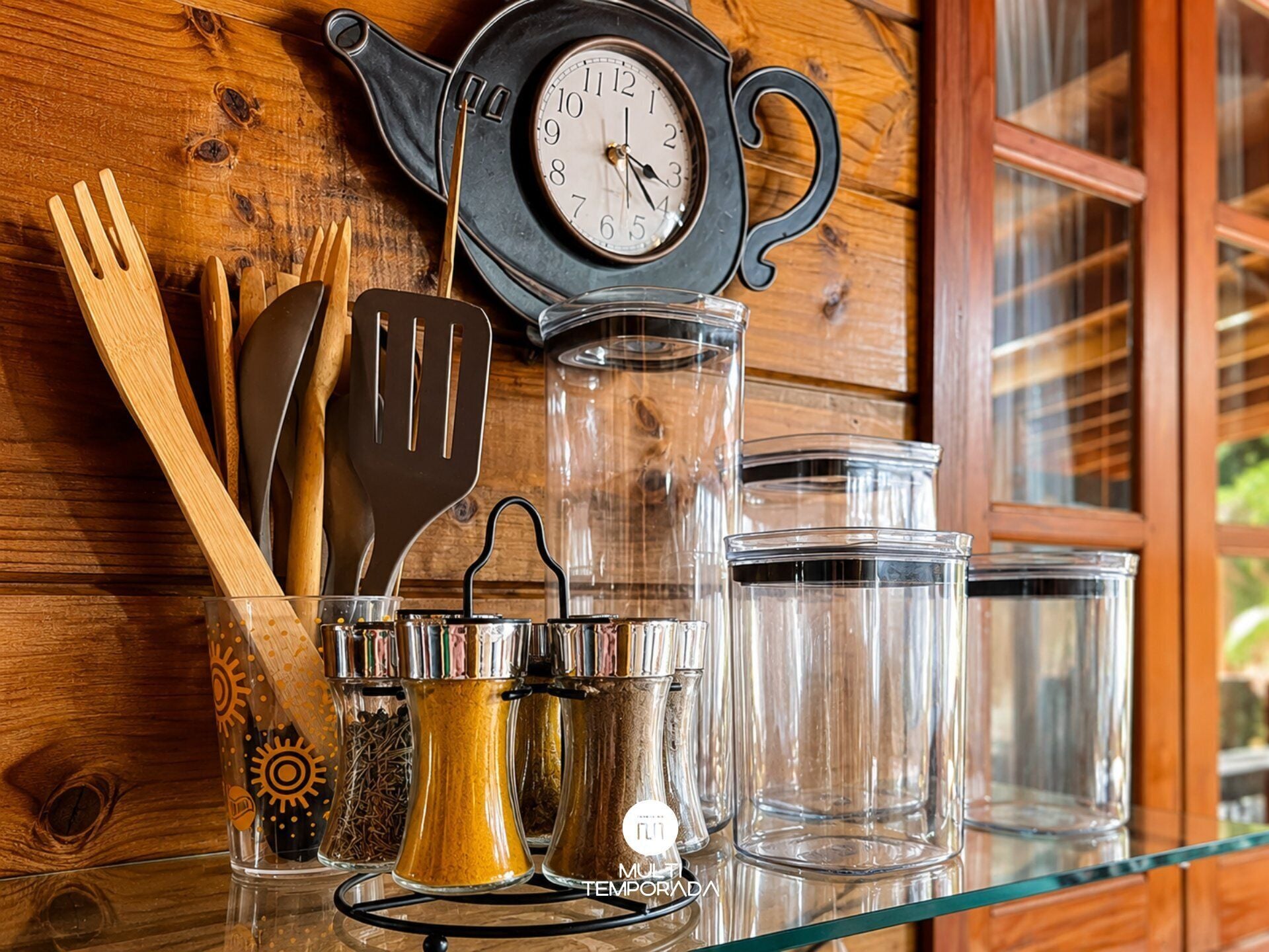 A kitchen setting with a clock, utensils, and containers on a wooden surface.