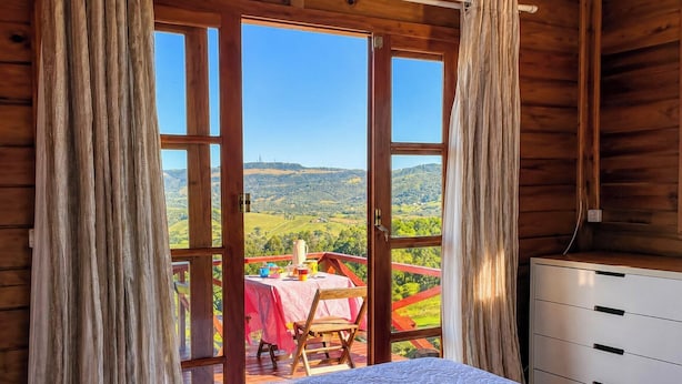 Una baita di legno con un balcone, un letto e un tavolo apparecchiato per la cena.
