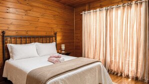 Una stanza con rivestimenti in legno, un letto, un comodino e una finestra con tende.