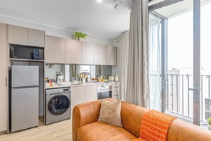 Kompakti keittiö, jossa on kodinkoneet, sohva ja suuri ikkuna.