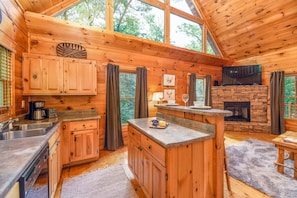 Ein Holzblockhaus-Interieur mit Küche, Essbereich und Kamin.