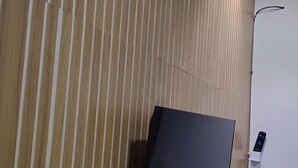 Een flatscreen televisie bevestigd aan een houten wand, met een houder voor de afstandsbediening.