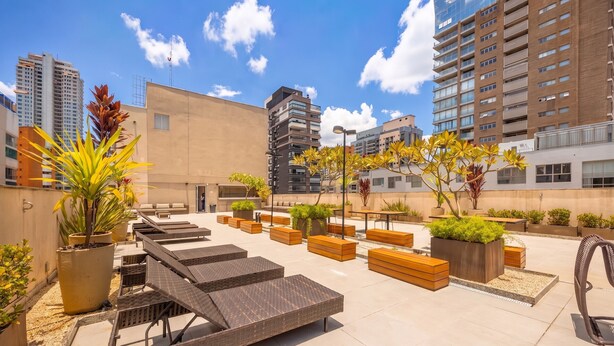 Terraza en la azotea con mobiliario exterior, jardineras y vistas de edificios circundantes.