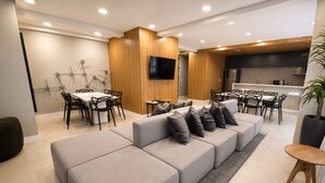 Una sala de estar moderna con sofá modular, comedor y cocina.