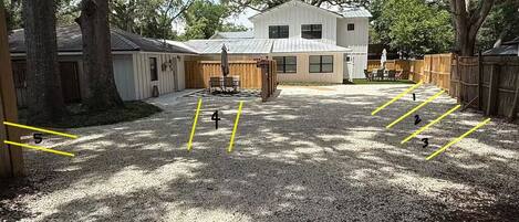 A gravel yard with numbered parking spaces, a wooden fence, and a building with a metal roof.