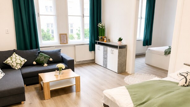 Um apartamento moderno com sofá, cama, pequena cozinha e amplas janelas.