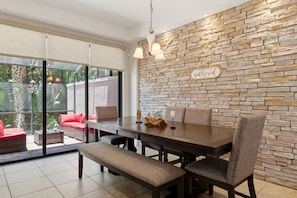 A dining area with a stone wall, a table, chairs, and a bench. - Enchanted Pines Retreat!  Near Disney with Resort Pool (Davenport)