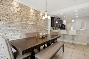 A dining area with a stone wall, a wooden table, and bar stools. - Enchanted Pines Retreat!  Near Disney with Resort Pool (Davenport)