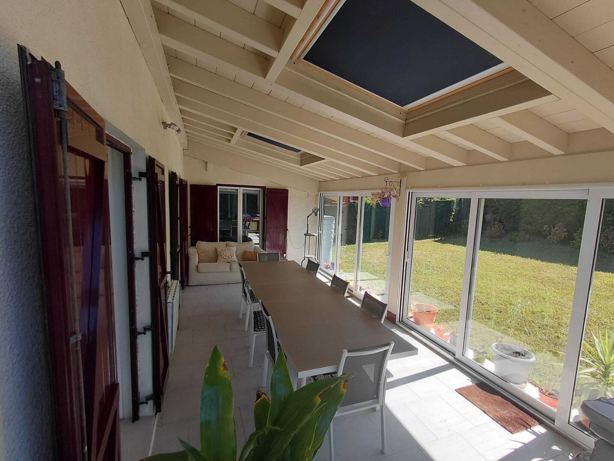 A spacious room with a long table, chairs, a sofa, and a sliding glass door leading to a garden.