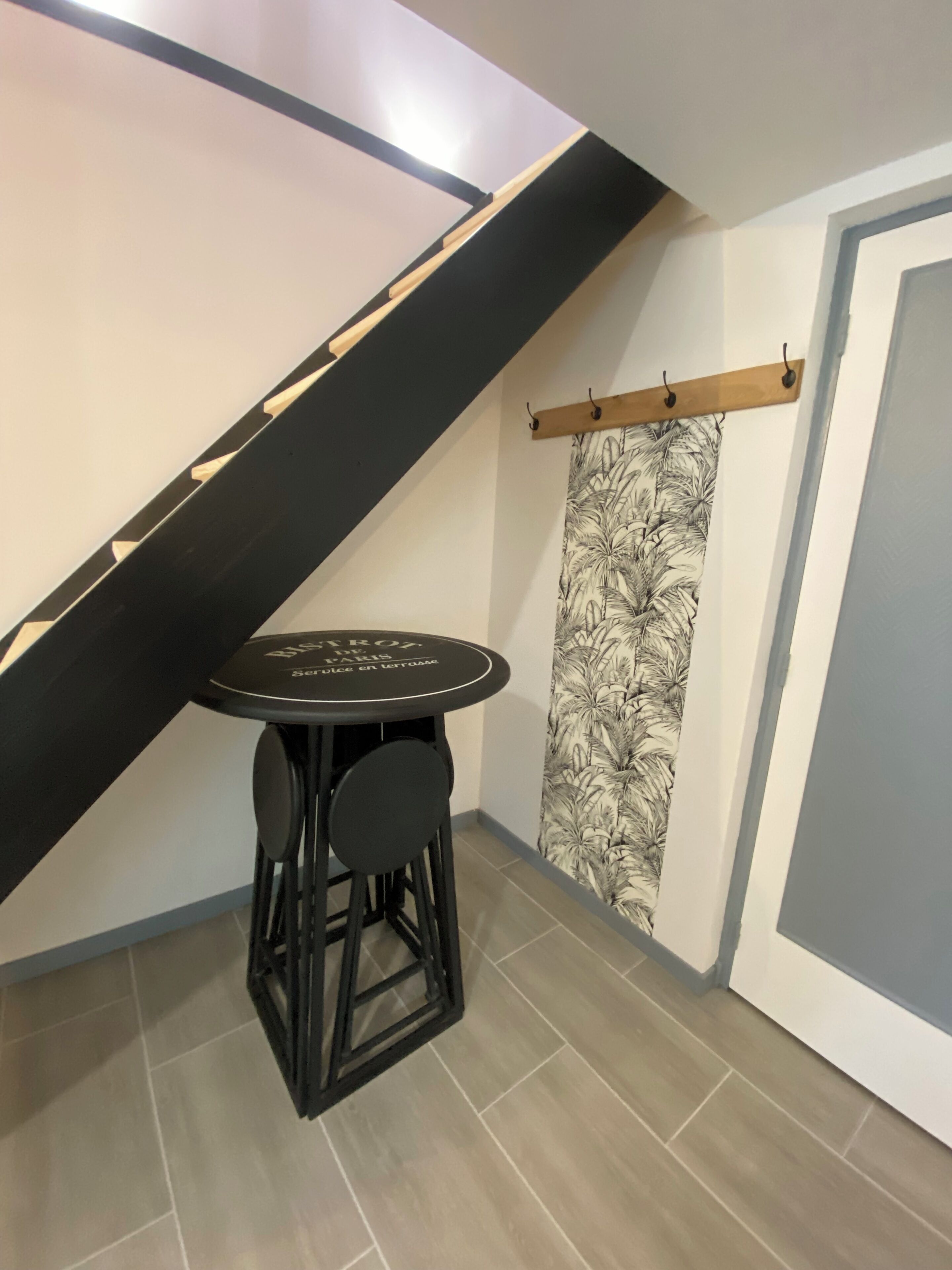 A small table with a stool, a black and white patterned curtain, and a wooden beam on the ceiling.