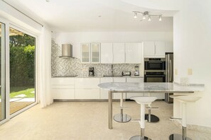 A modern kitchen with a marble countertop, stainless steel appliances, and a sliding glass door to the outdoors. - Air Conditioning in the Living Room • Private Pool • Modern (Sosúa)