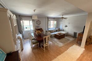 A spacious living area with a dining table, sofa, and a ceiling fan. - 1A171 CBM Gijón: Apartment near the beach (Gijón)