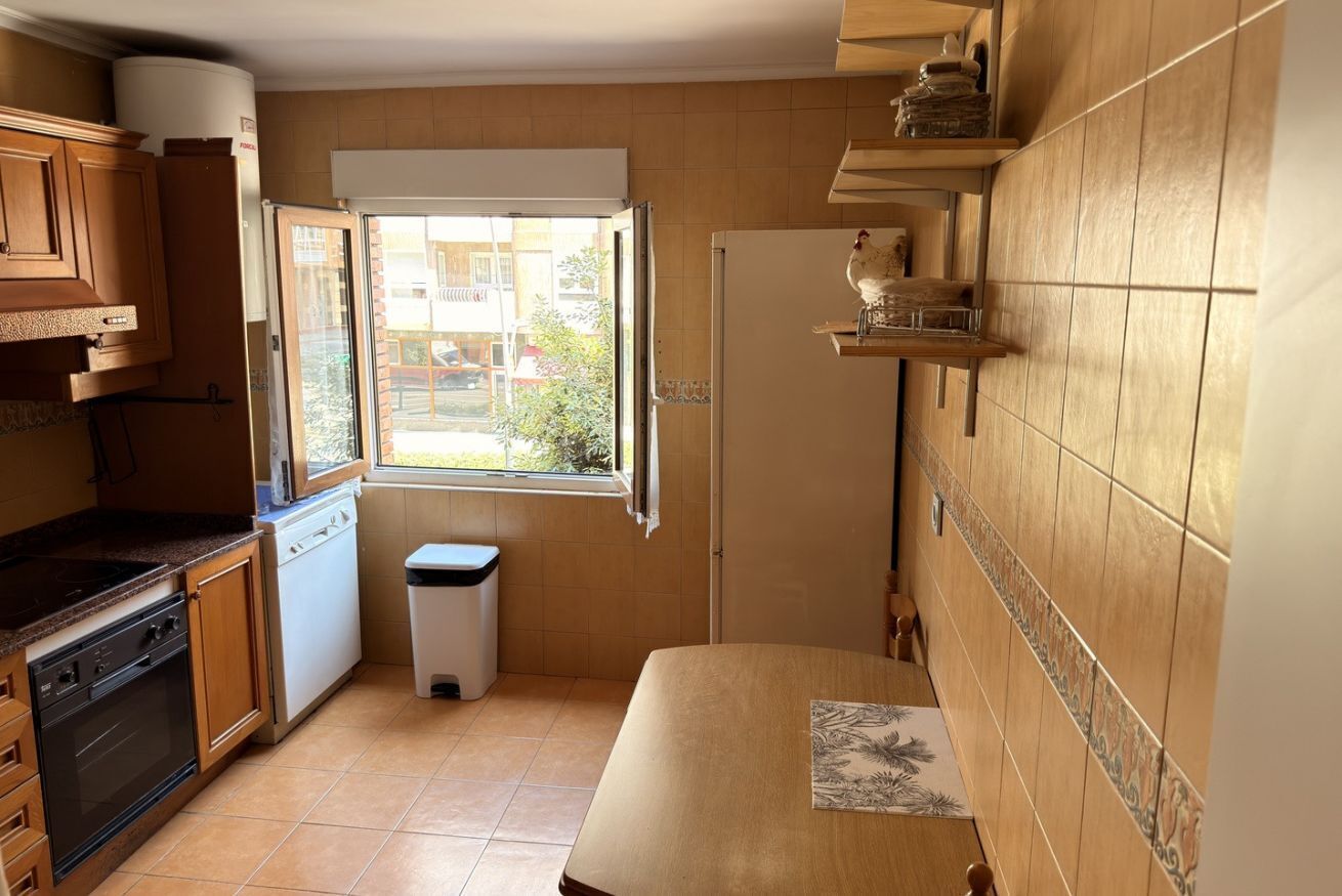 Uma cozinha compacta com janela, armários de madeira, micro-ondas e pia.