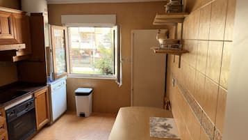 Uma cozinha compacta com janela, armários de madeira, micro-ondas e pia.