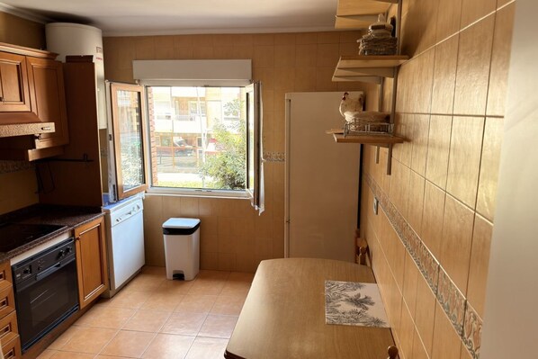 A compact kitchen with a window, wooden cabinets, a microwave, and a sink.