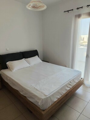 Una camera da letto con un letto, una testiera, un lampadario e una finestra con tende.