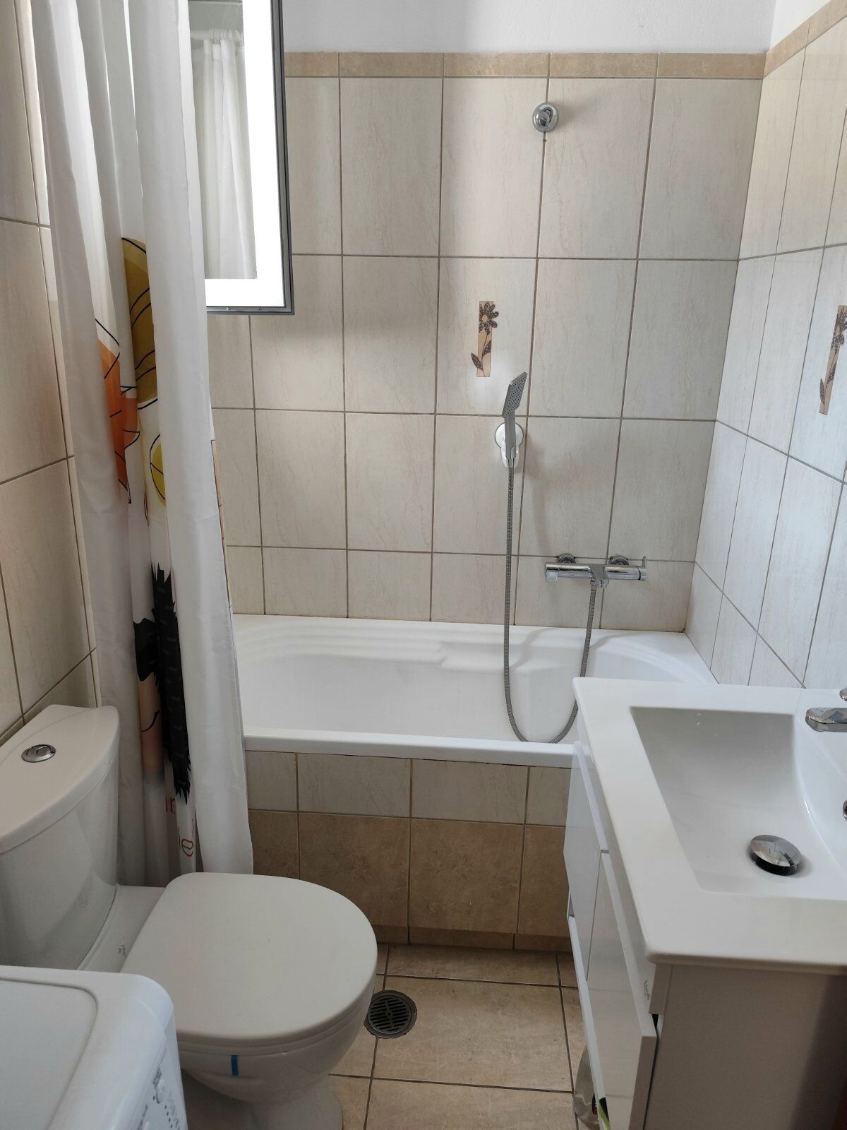 Een kleine badkamer met toilet, bad en wastafel.