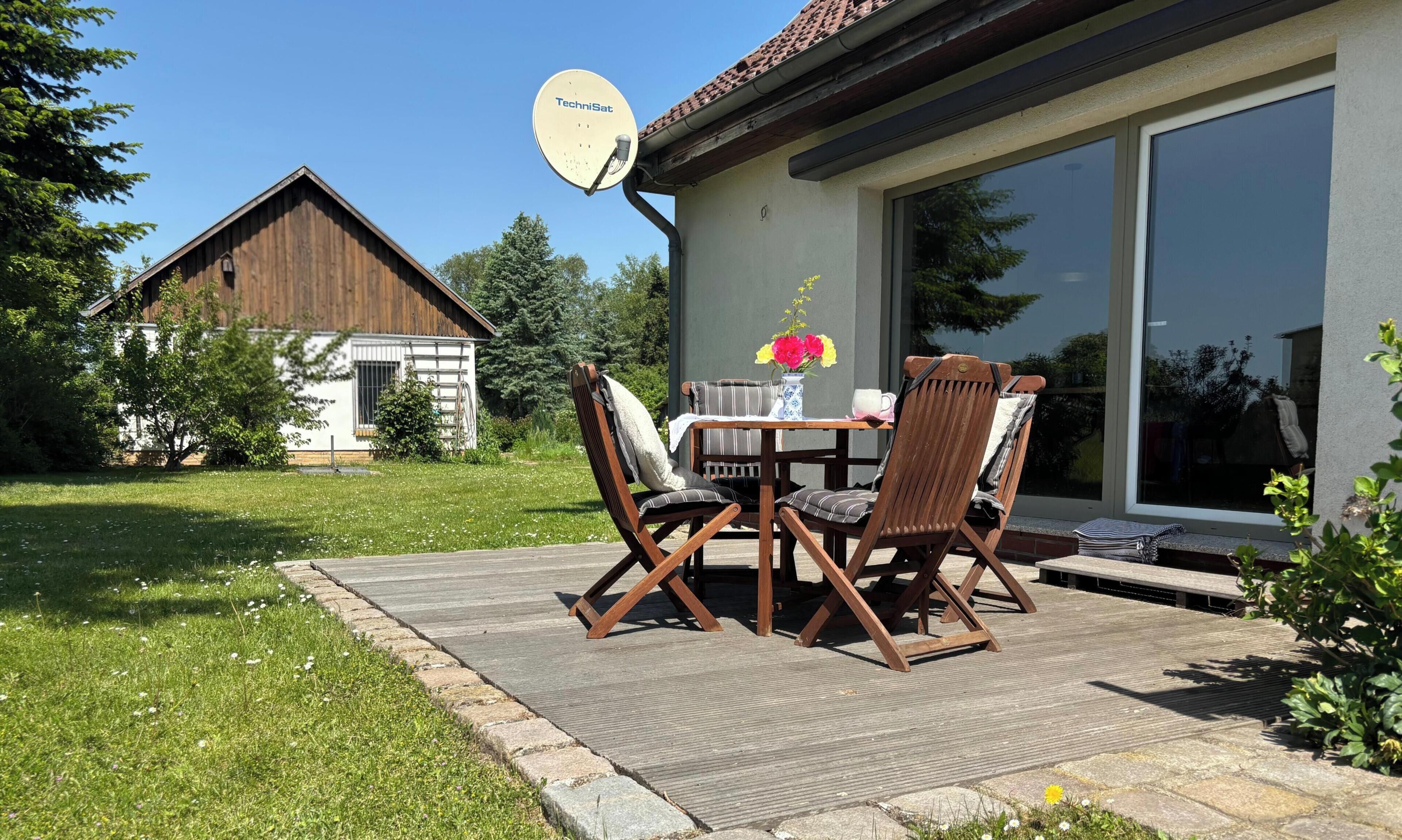 A patio with a table and chairs, a satellite dish, and a large window.
