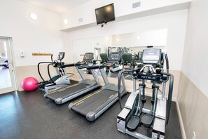 Ein Fitnessstudio mit Laufbändern, Crosstrainern und einem stationären Fahrrad.