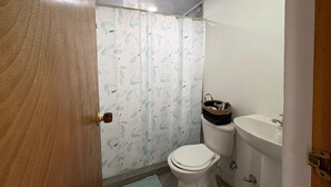 A bathroom with a toilet, a sink, and a shower curtain with a leaf pattern. - 7 colors available / AC / Airport pickup (San Andrés)