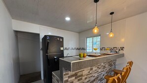 A modern kitchen with a built-in refrigerator, a stone backsplash, wooden bar stools, and pendant lighting. - 7 colors available / AC / Airport pickup (San Andrés)