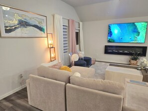 A living room with a sofa set, a flat-screen TV, a painting, and a window with curtains. - Cozy Luxury Getaway near Frisco and Prosper (Krugerville)