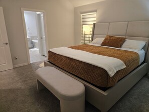 Ein Schlafzimmer mit Bett, einer Bank, einer Tür und einem Flur.