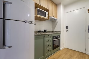 Eine Küche mit Kühlschrank, Mikrowelle, Backofen und Holzschränken.
