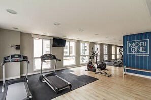 Un gimnasio con cintas de correr, bicicletas estáticas y una pared con la marca 'MOBILE ONE PINHEIROS'.