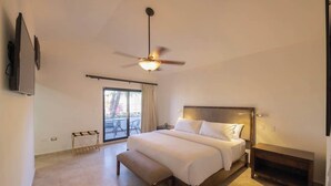 Une chambre à coucher comprenant un lit, un ventilateur de plafond, une table de chevet, un banc et un téléviseur fixé au mur.